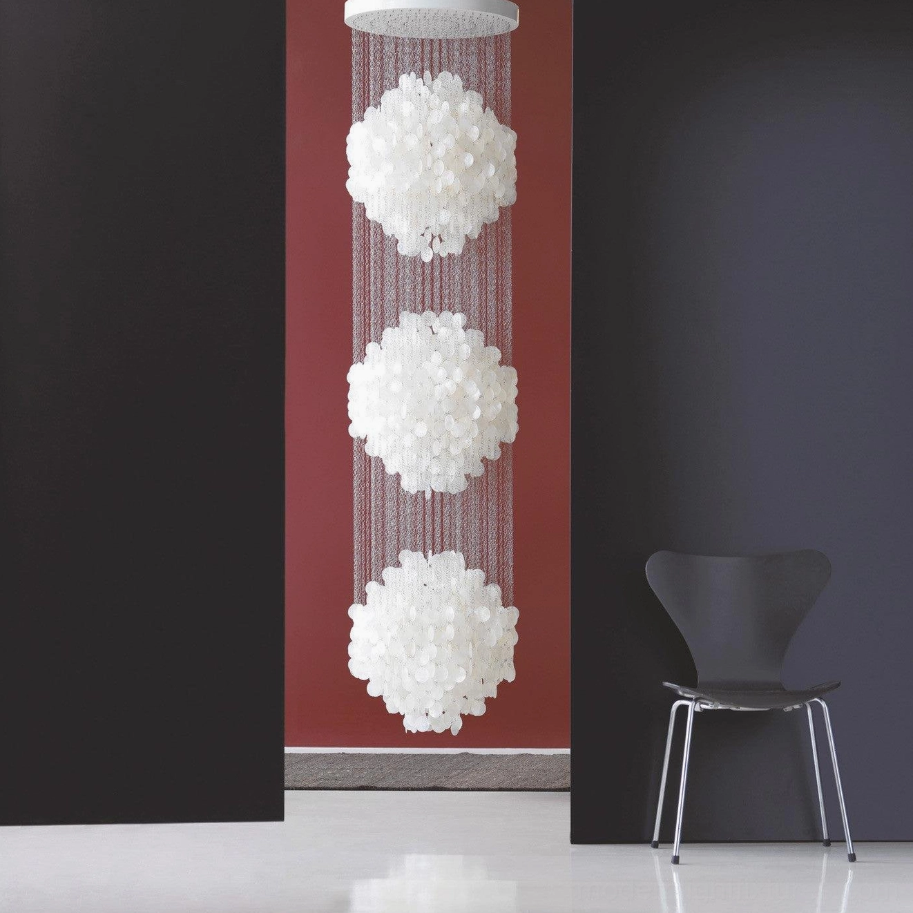 Vertical triple layer white shell pendant light with long metal suspension cords in modern minimalist home