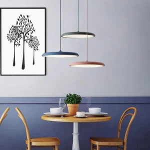 Three modern disc pendant lights in blue, gray, and terracotta hanging above small dining table