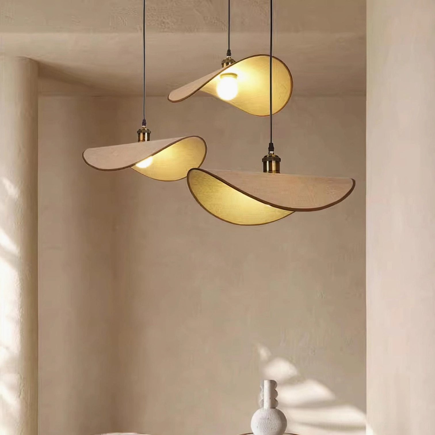 Set of three matching handcrafted pendant lights with warm fabric shades and brass-toned holders in overhead residential view