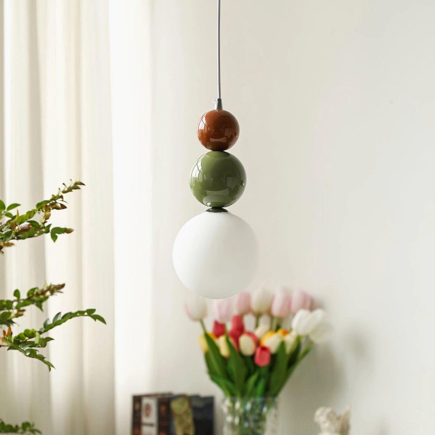 Hanging globe pendant light fixture in cozy residential setting with tulips and green plants by windowsill