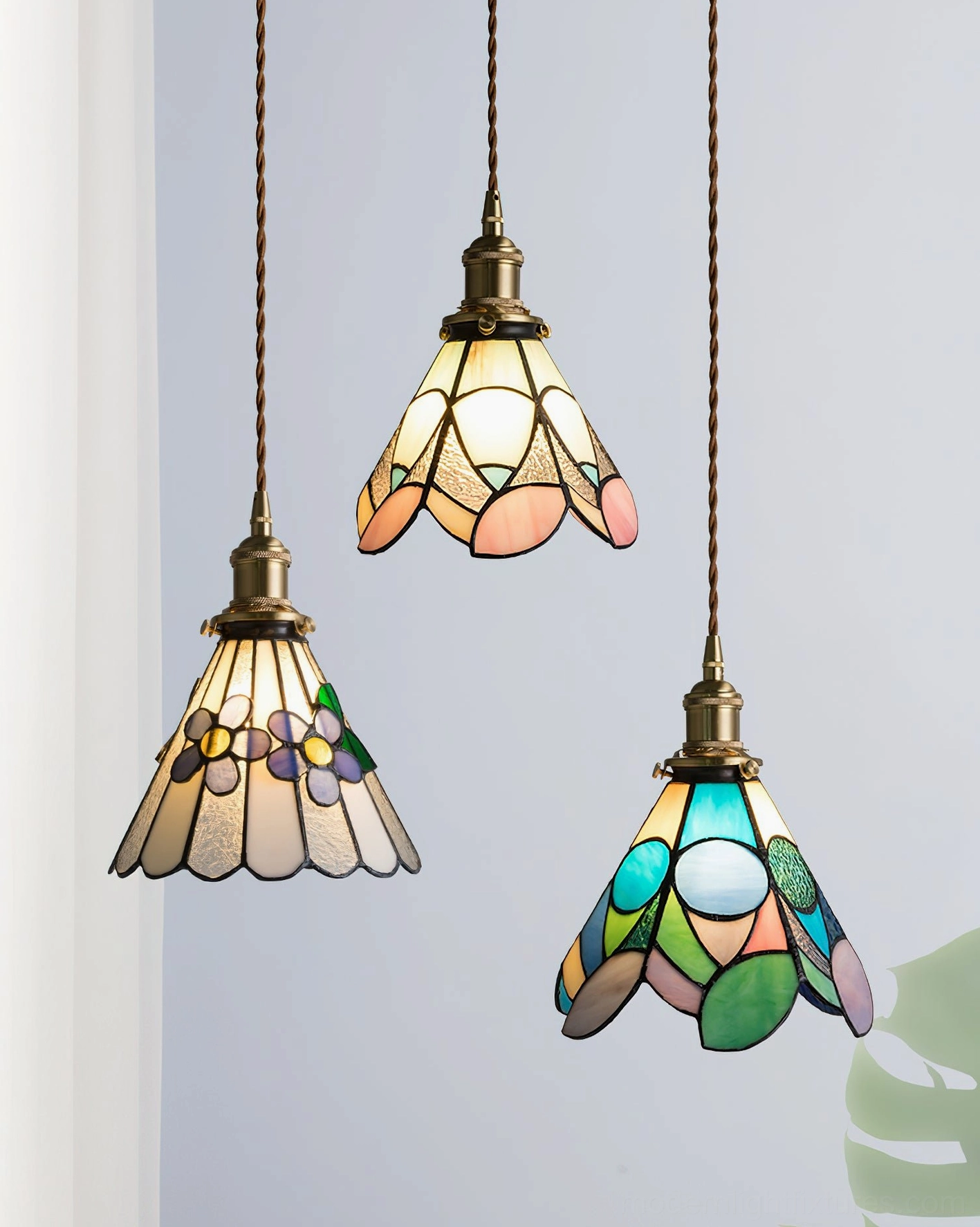 Set of three handcrafted stained glass pendant lamps with different shade designs overhead view showing brass twisted cords