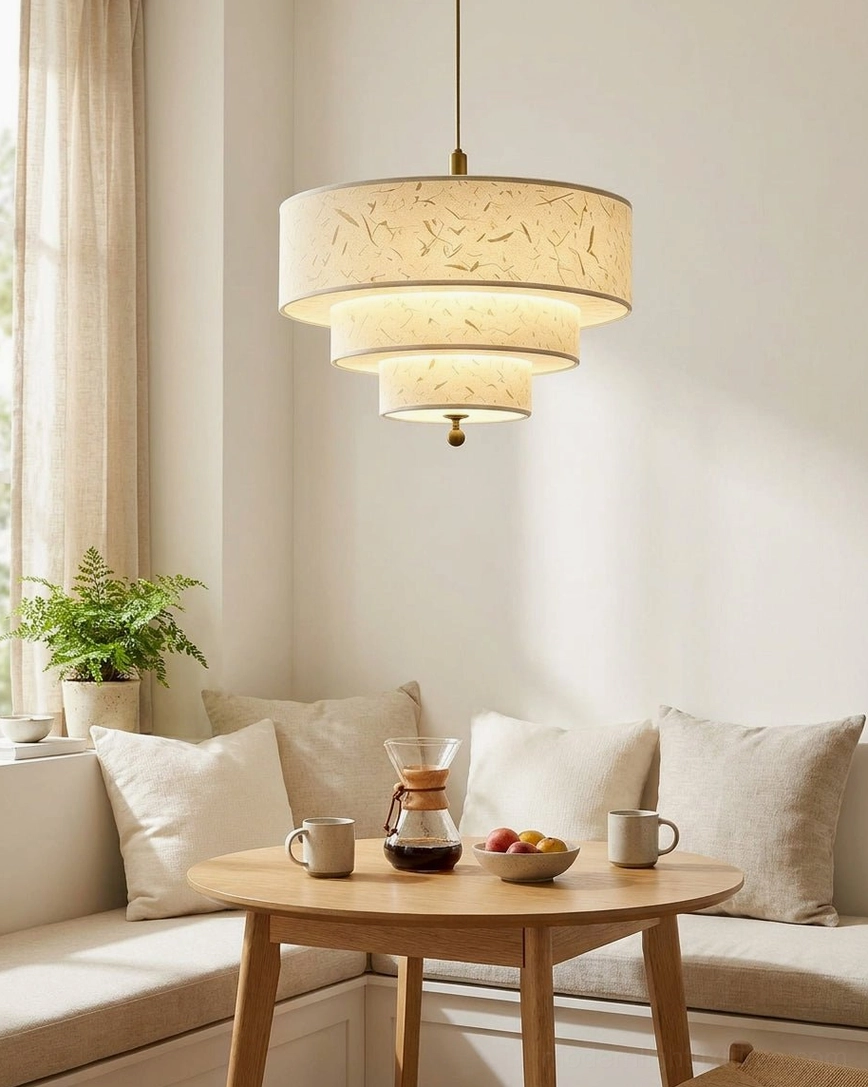 Cascading drum pendant suspended above breakfast nook with warm home decor, casual setting, natural daylight