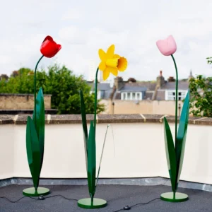 Three tulip floor lamps in red, pink, and yellow blooms with green stems on rooftop outdoor setting – multi-color botanical floor lighting