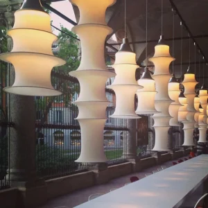 Contemporary tiered pendant lights in commercial dining area with warm illumination and linear arrangement