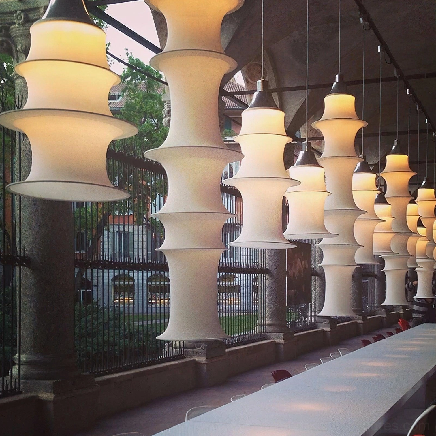 Contemporary tiered pendant lights in commercial dining area with warm illumination and linear arrangement