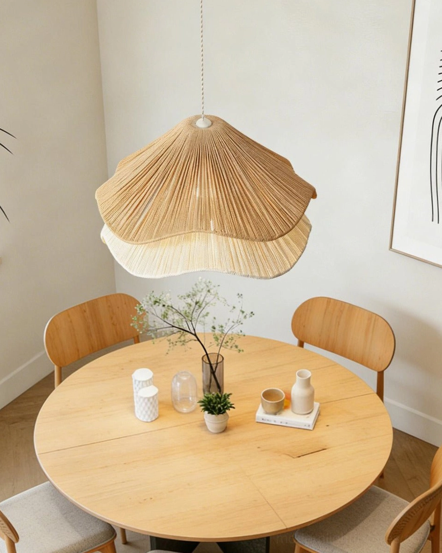 Tiered natural jute pendant light illuminated above round wooden dining table, organic modern interior styling