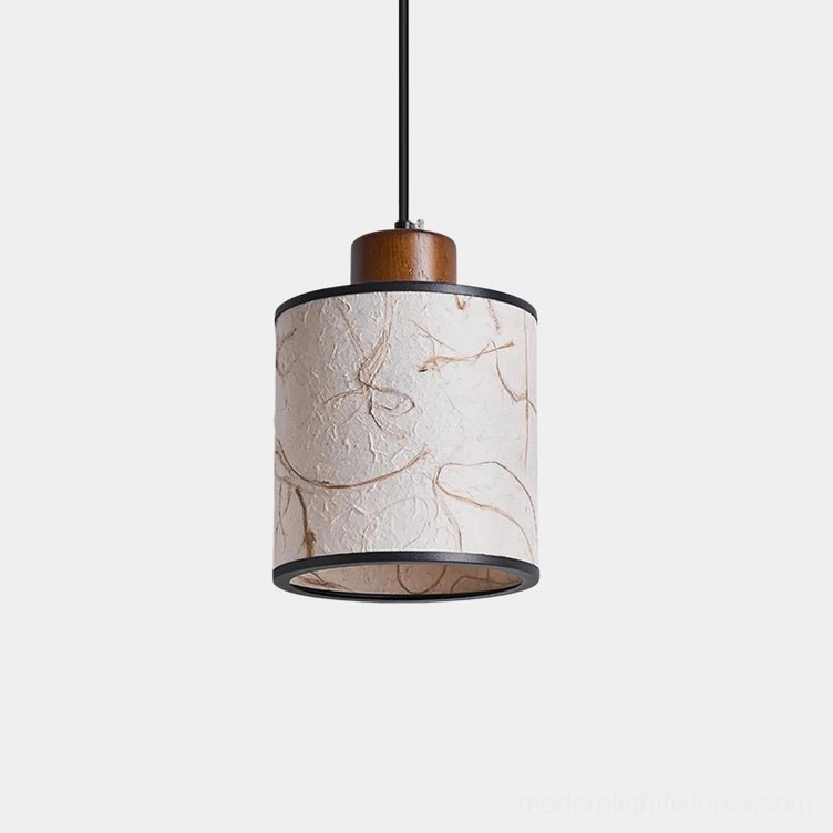 Tierra handmade pendant light with textured rice paper cylinder shade, black metal frame, and wooden accent cap in studio setting
