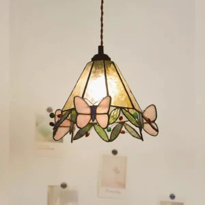 Lit Tiffany style pink butterfly pendant light glowing warm light indoors, illuminated stained glass fixture on wall background