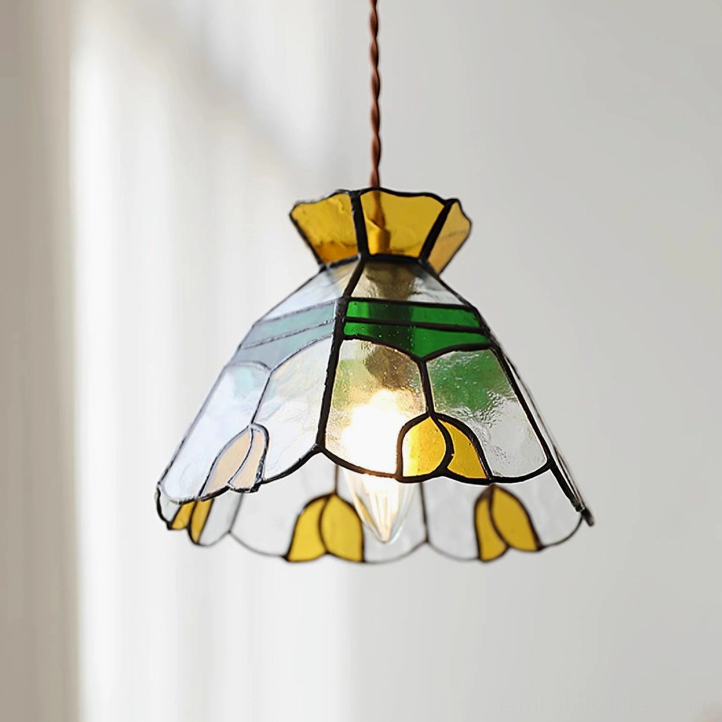 Close-up detail of Tiffany stained glass pendant shade showing hand-crafted floral patterns, colored glass tiles, and brass frame construction