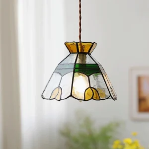 Illuminated Tiffany stained glass pendant light hanging in cozy home setting with warm amber and green glass tones, twisted brown suspension cord