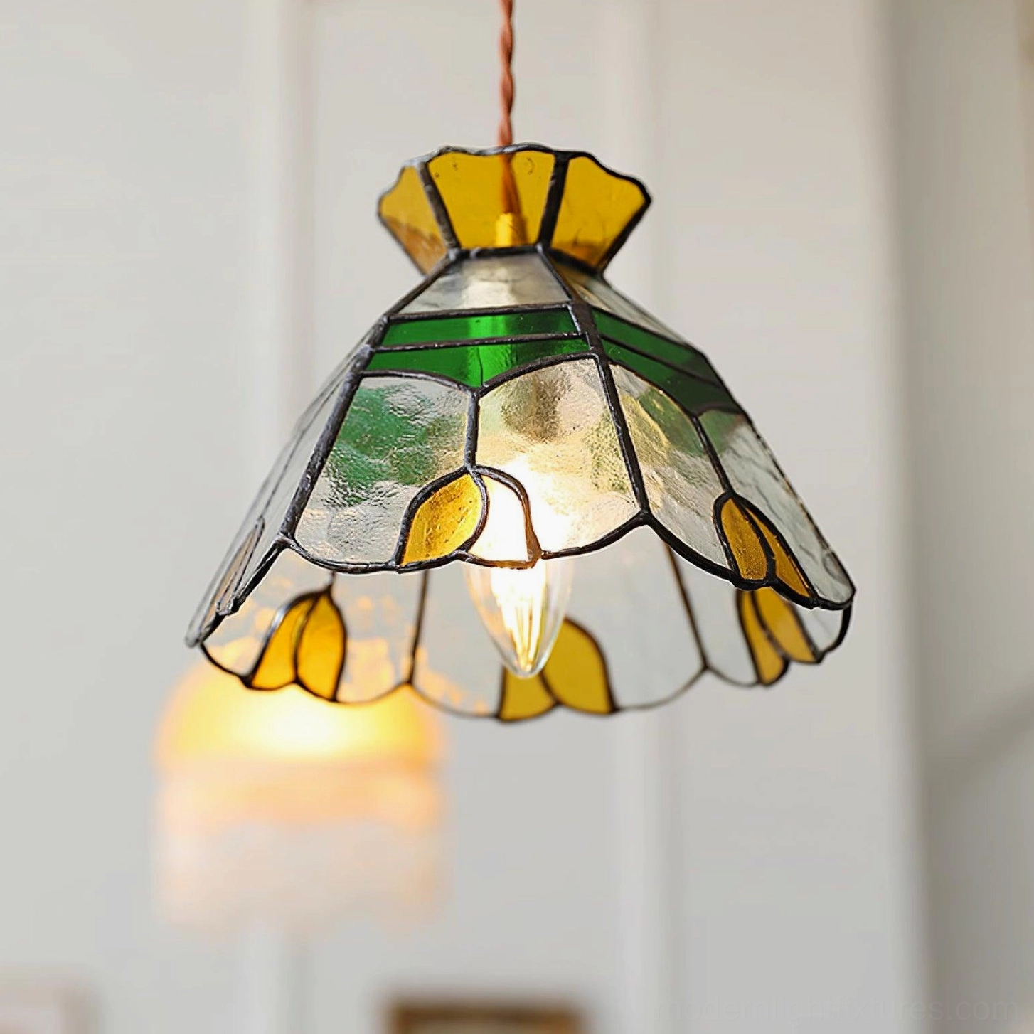 Reverse overhead view of illuminated Tiffany stained glass pendant lamp showing internal bulb and complete shade structure
