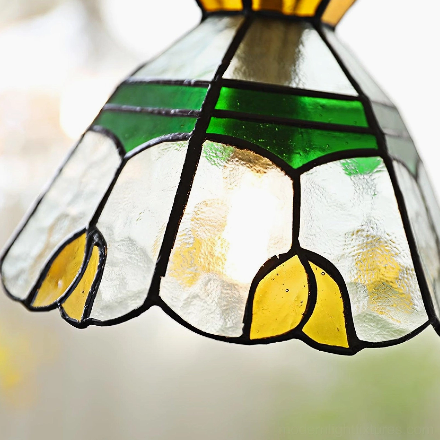 Tiffany stained glass pendant light fixture suspended in living space, hand-crafted botanical design with emerald and amber tones