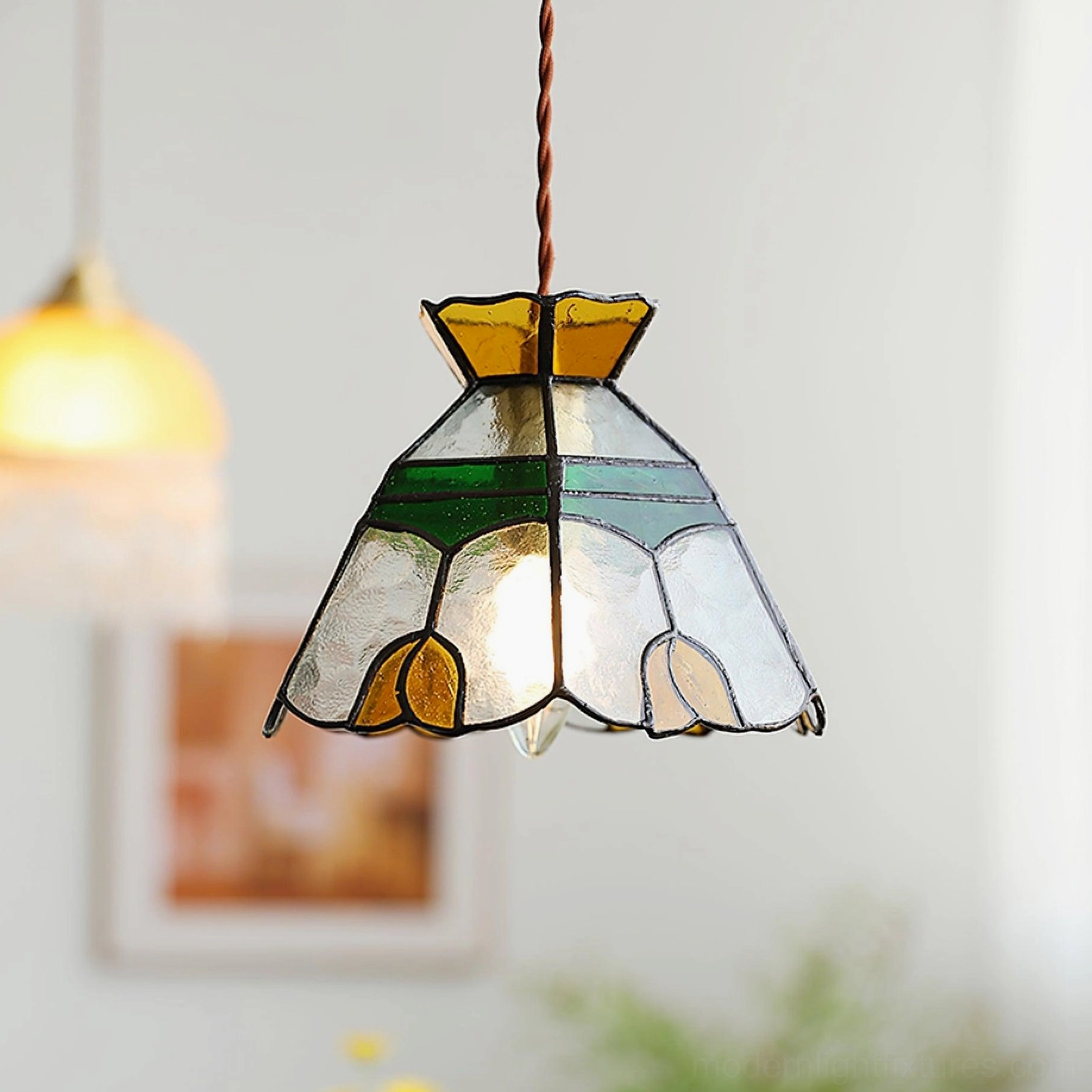 Right three-quarter angle of illuminated Tiffany stained glass pendant with visible warm glowing bulb and detailed glass shade