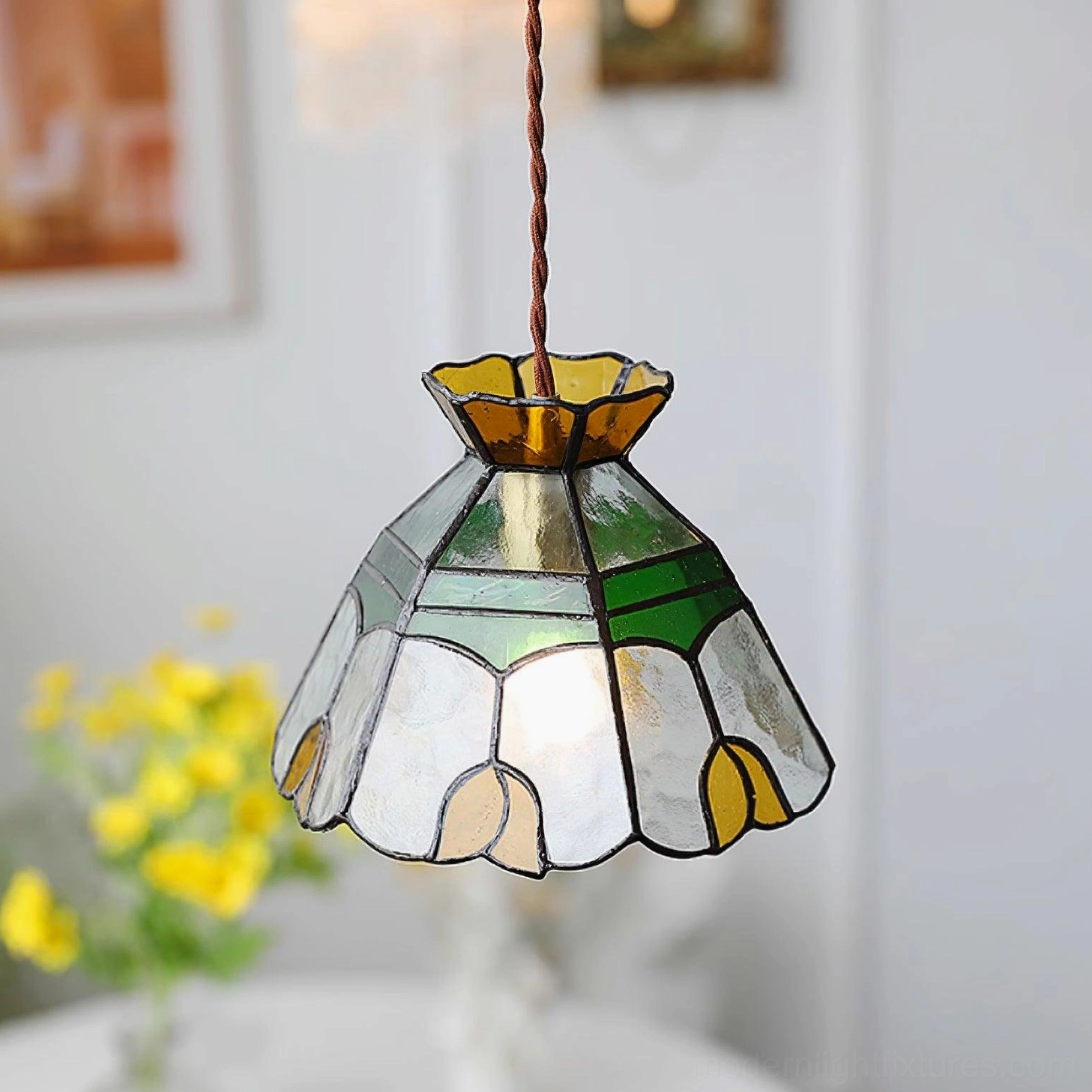 Decorative Tiffany stained glass pendant light highlighting warm amber and emerald green colored glass panels in artistic arrangement