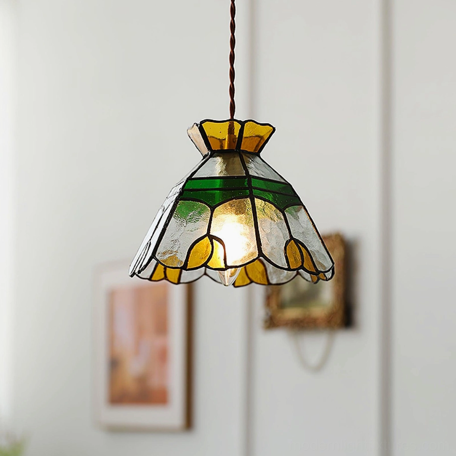 Left three-quarter view of Tiffany pendant lamp illuminated, showing detailed glass shade construction with brown twisted cord in home interior