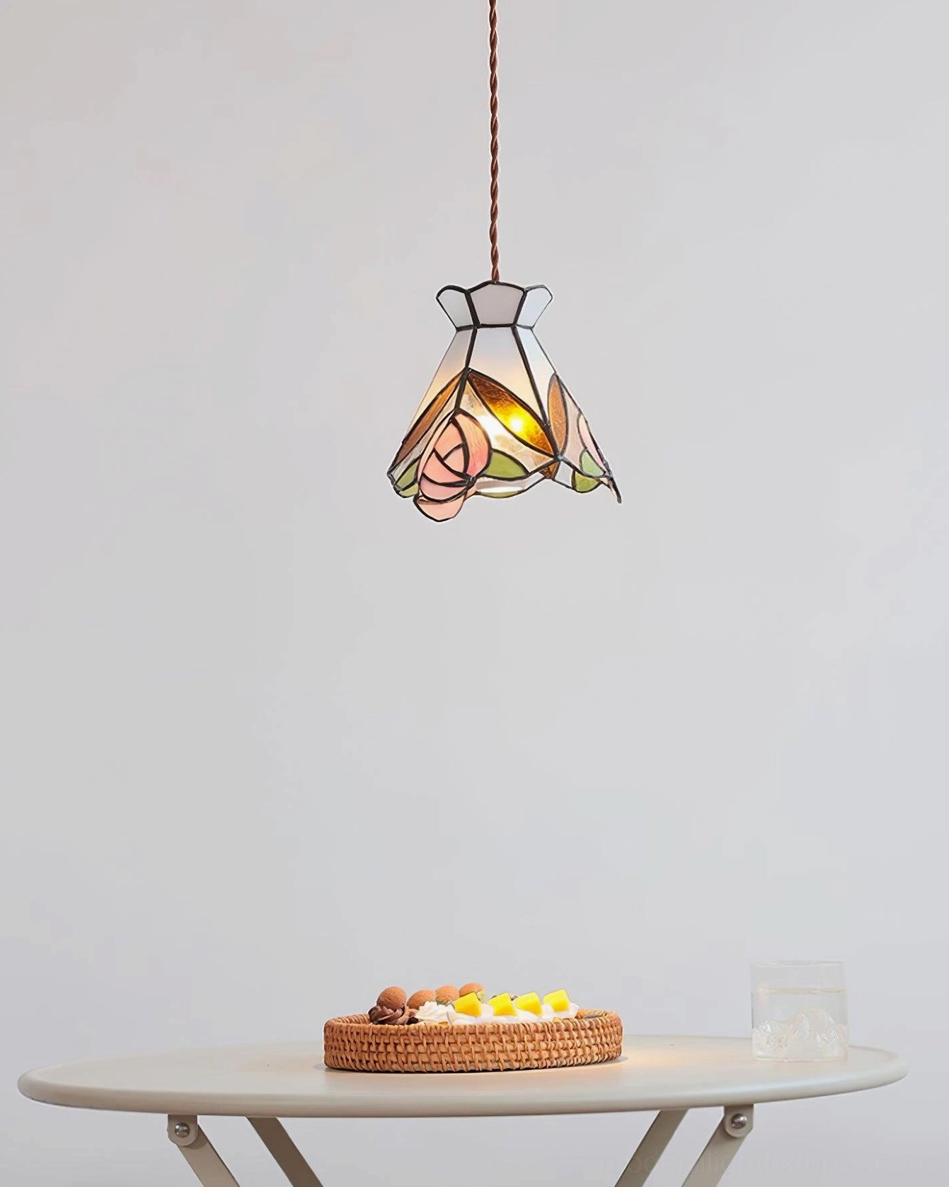 Vintage Tiffany rose pendant lamp suspended above white dining table with dessert service below