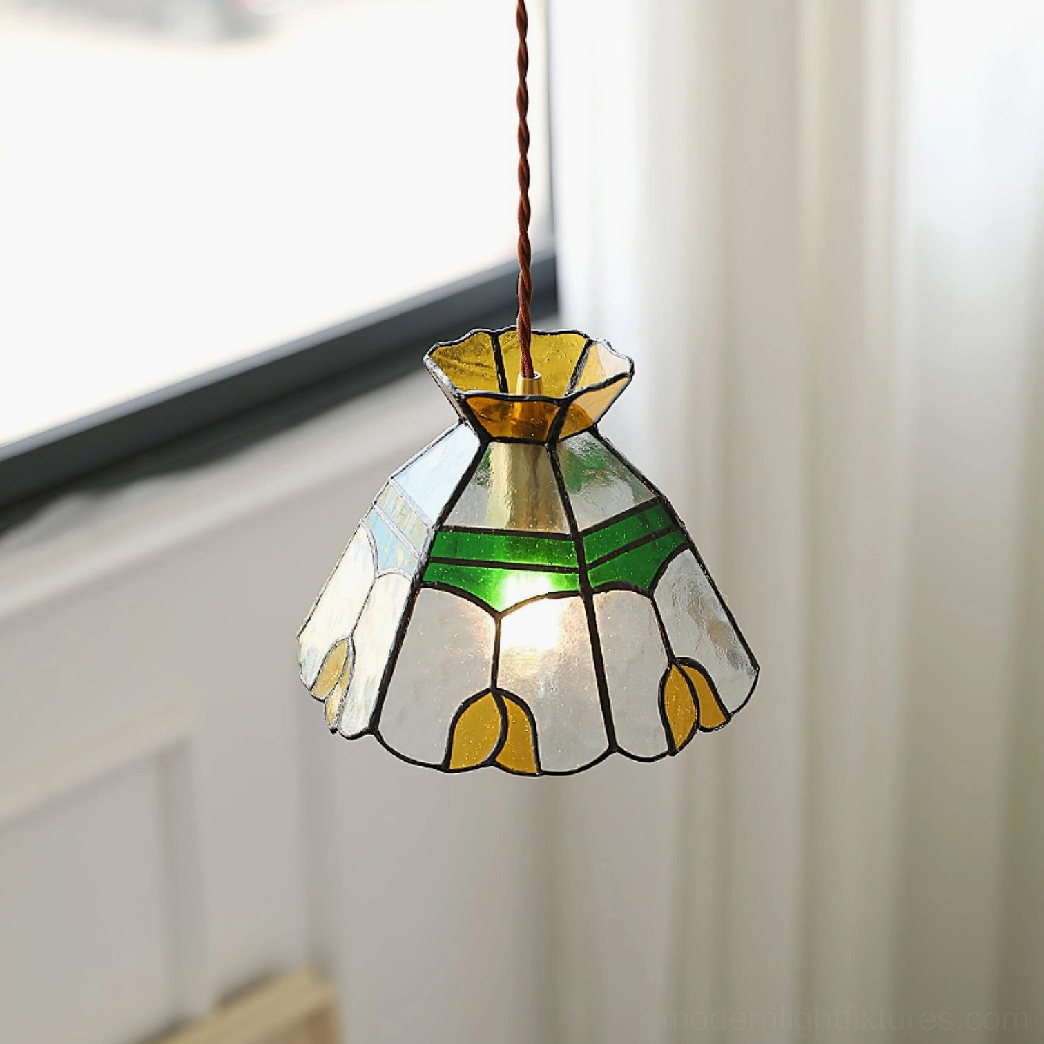Bottom view of Tiffany stained glass pendant lamp showing intricate hand-crafted glass patterns with tulip motifs and warm interior glow