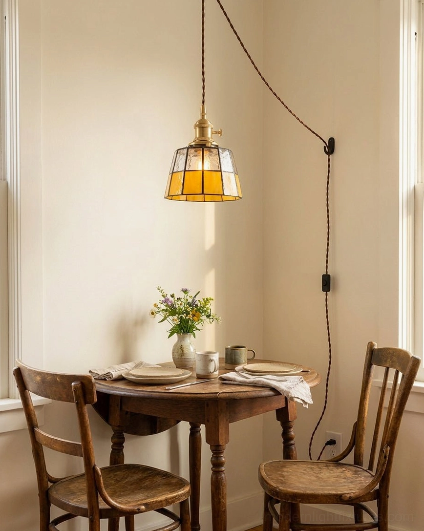 Overhead view of warm amber stained glass pendant light illuminating small rustic dining table with wooden chairs and home decor
