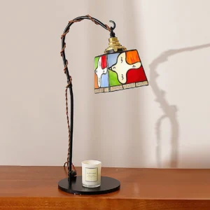 Tiffany-style stained glass arc lamp three-quarter view, wooden side table with scented candle, brown twisted power cord