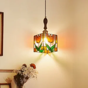 Vintage Tiffany-style pendant lamp with blooming tulip design illuminated in warm light, three-quarter view in cozy home corner setting
