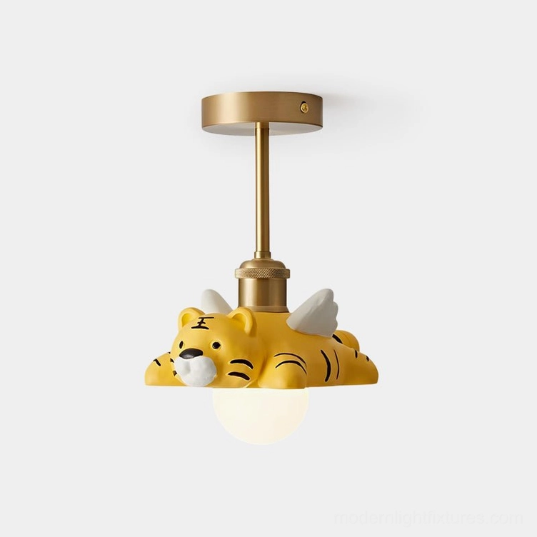 Tiger ceiling light fixture with brass metal wings and yellow resin animal figure perched on frosted glass orb, studio front close-up view