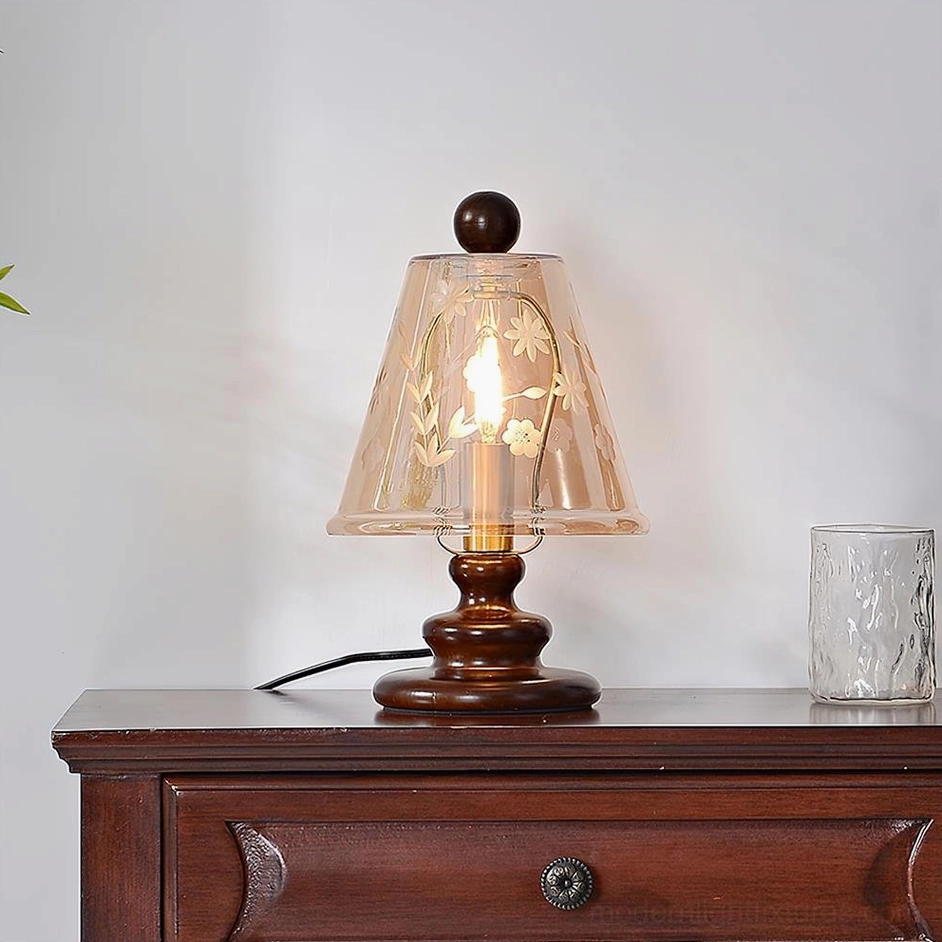 Tilda table lamp with walnut color wood base and cognac amber glass, displayed on wooden dresser with decorative glass cup