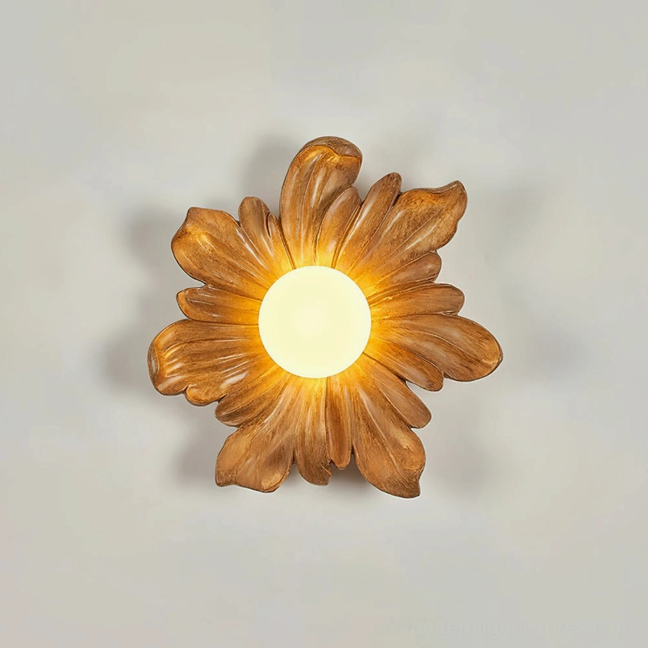 Natural wood Tina flower wall lamp mounted on light gray wall, matte petal frame with warm glowing light center