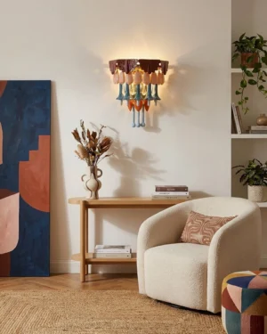 Tintora ceramic wall sconce mounted on neutral wall in modern bohemian living room with warm ambient lighting creating soft glow and refracted light from glass droplets