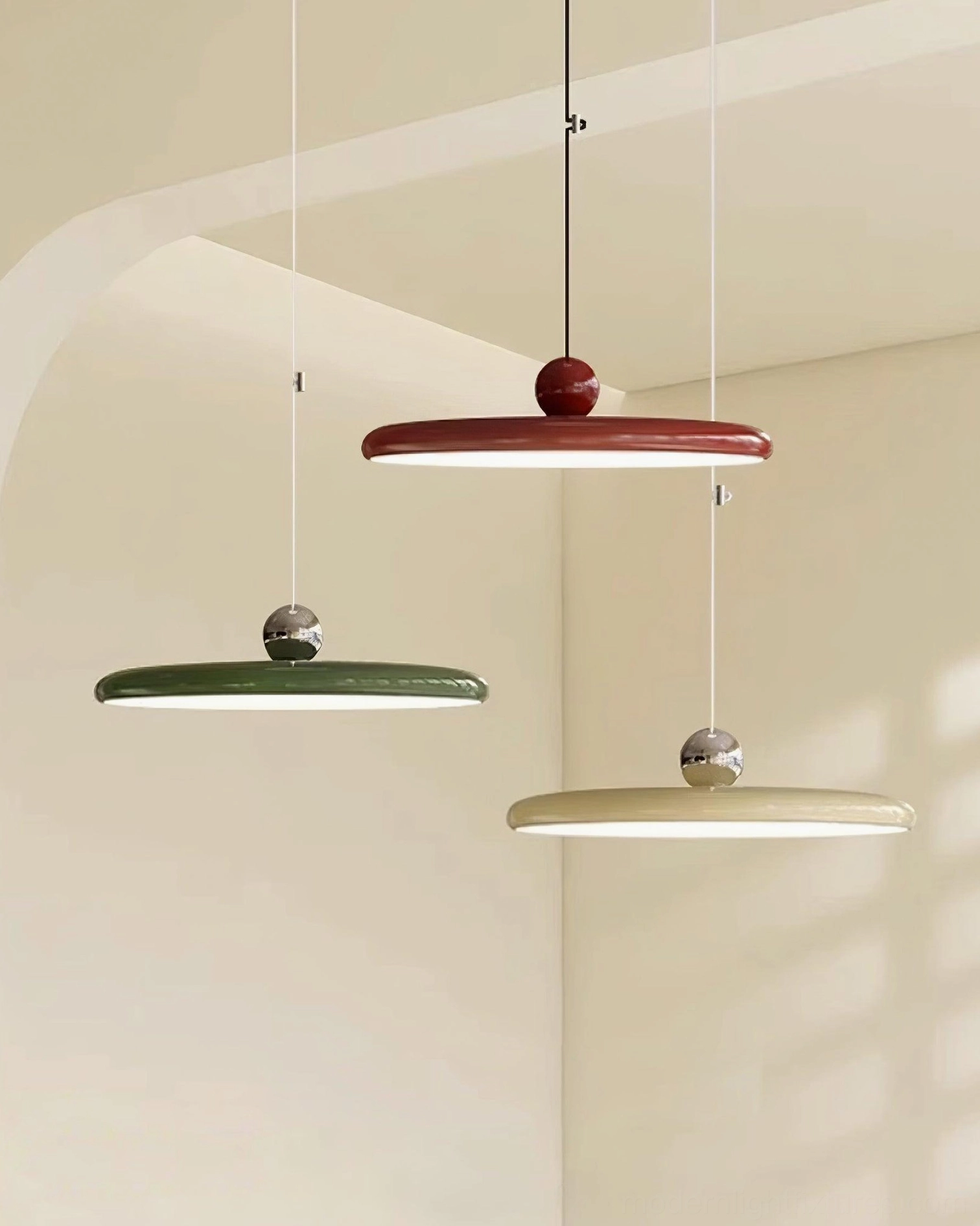 Multiple color variants of modern disc pendant lights displayed together including burgundy, green, and white