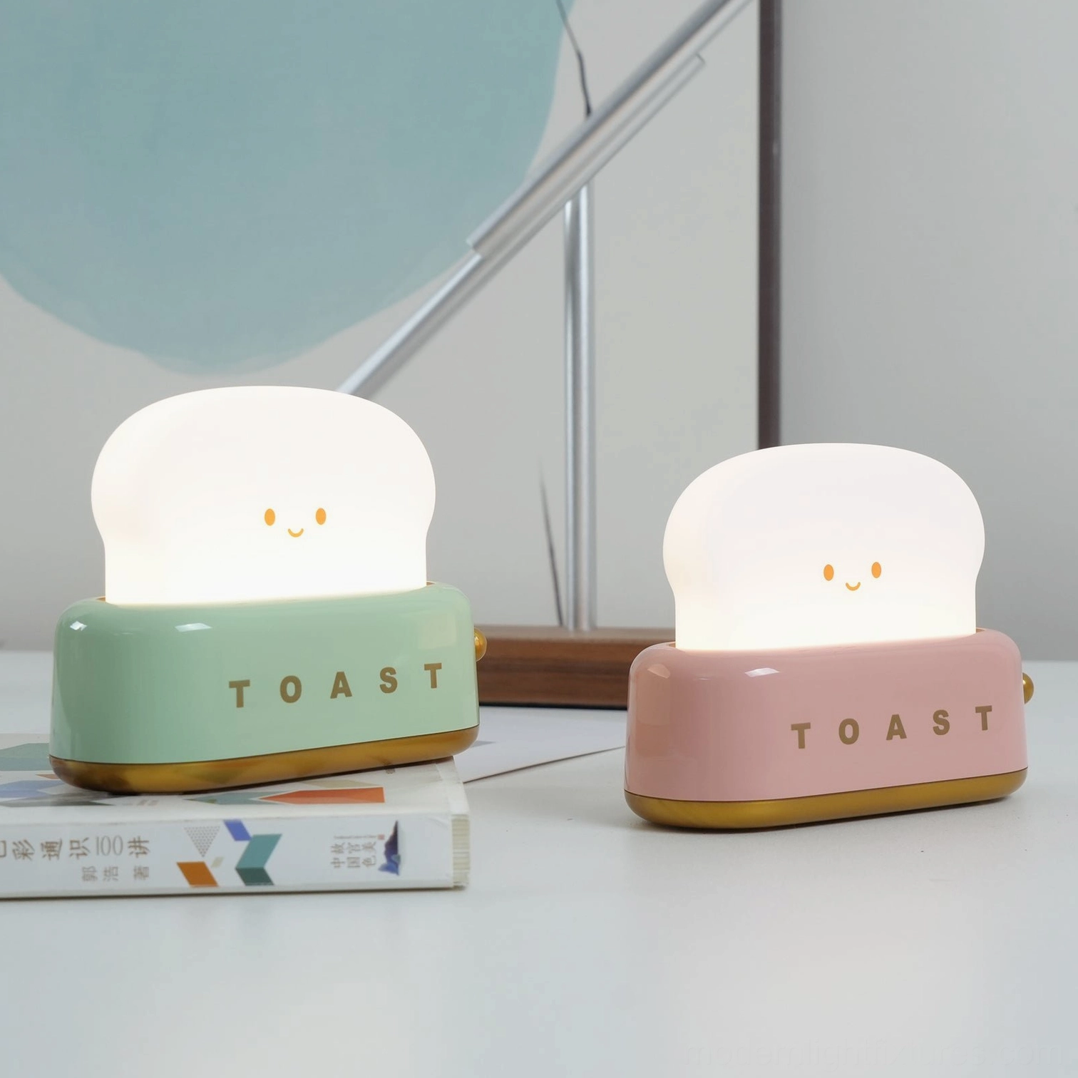 Pair of retro toaster lamps in green and pink on minimalist home office desk with warm lighting