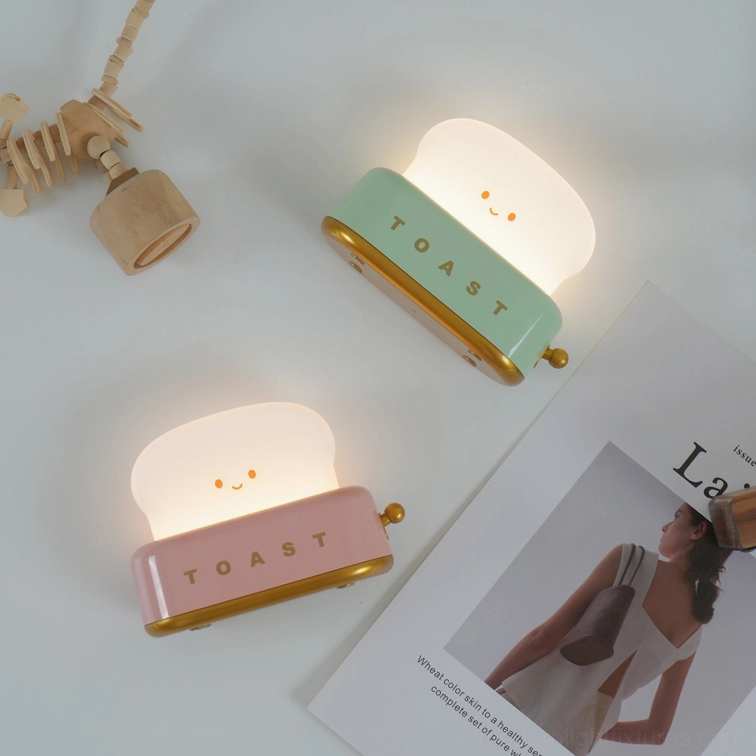 Set of two toaster table lamps in green and pink flat lay with magazines and home décor accents