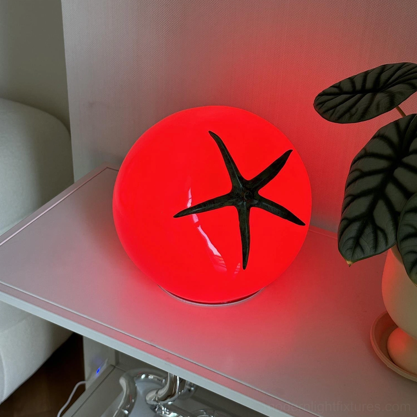 Illuminated tomato table lamp on bedroom nightstand with warm white 3000K LED glow next to potted green plant