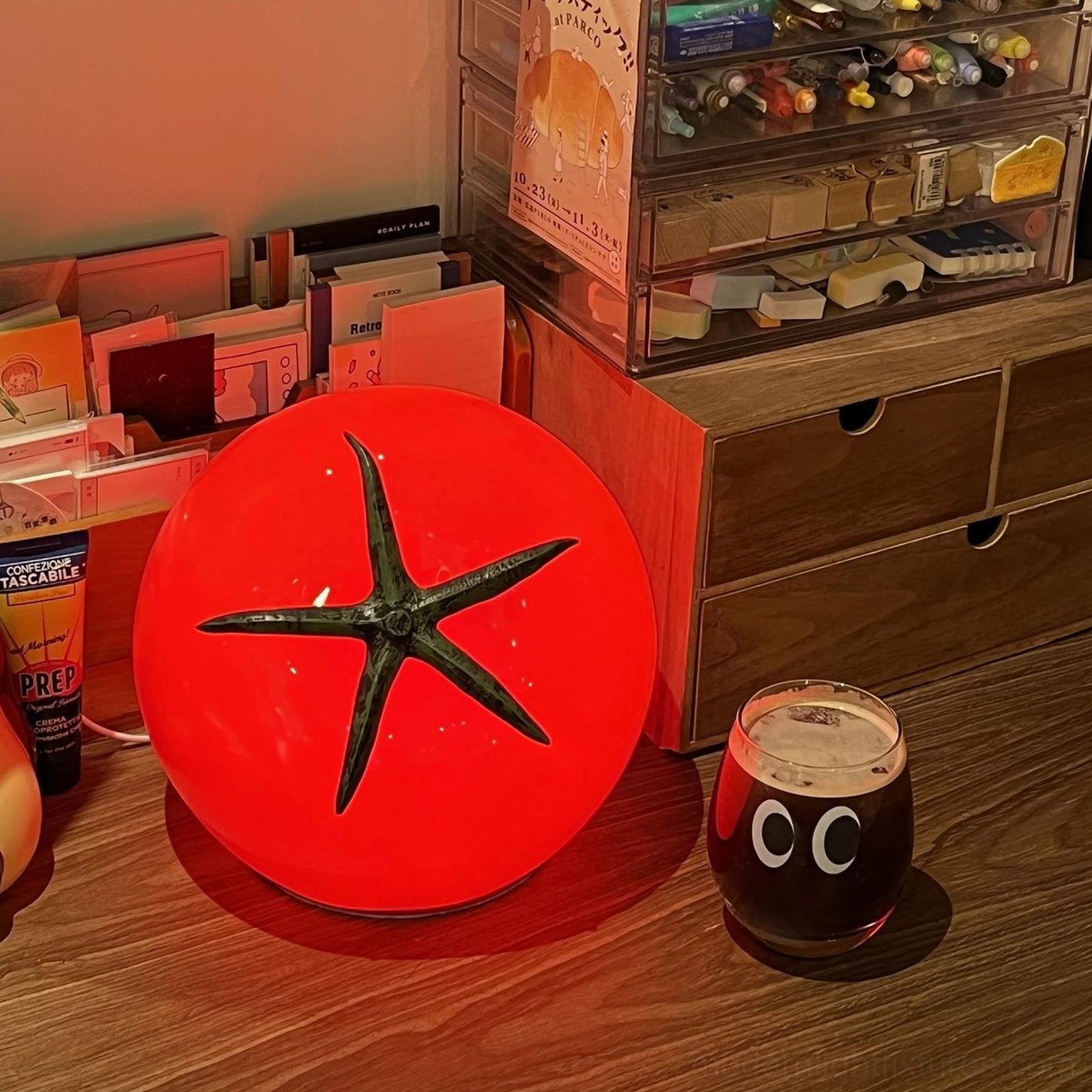 Tomato table lamp close-up detail of glossy red resin body with green stem calyx