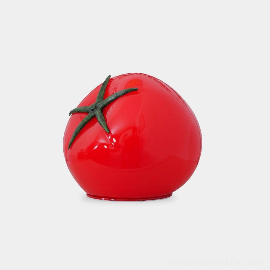 Tomato resin table lamp with glossy red body and green stem, front studio view showing modern artistic LED lighting design