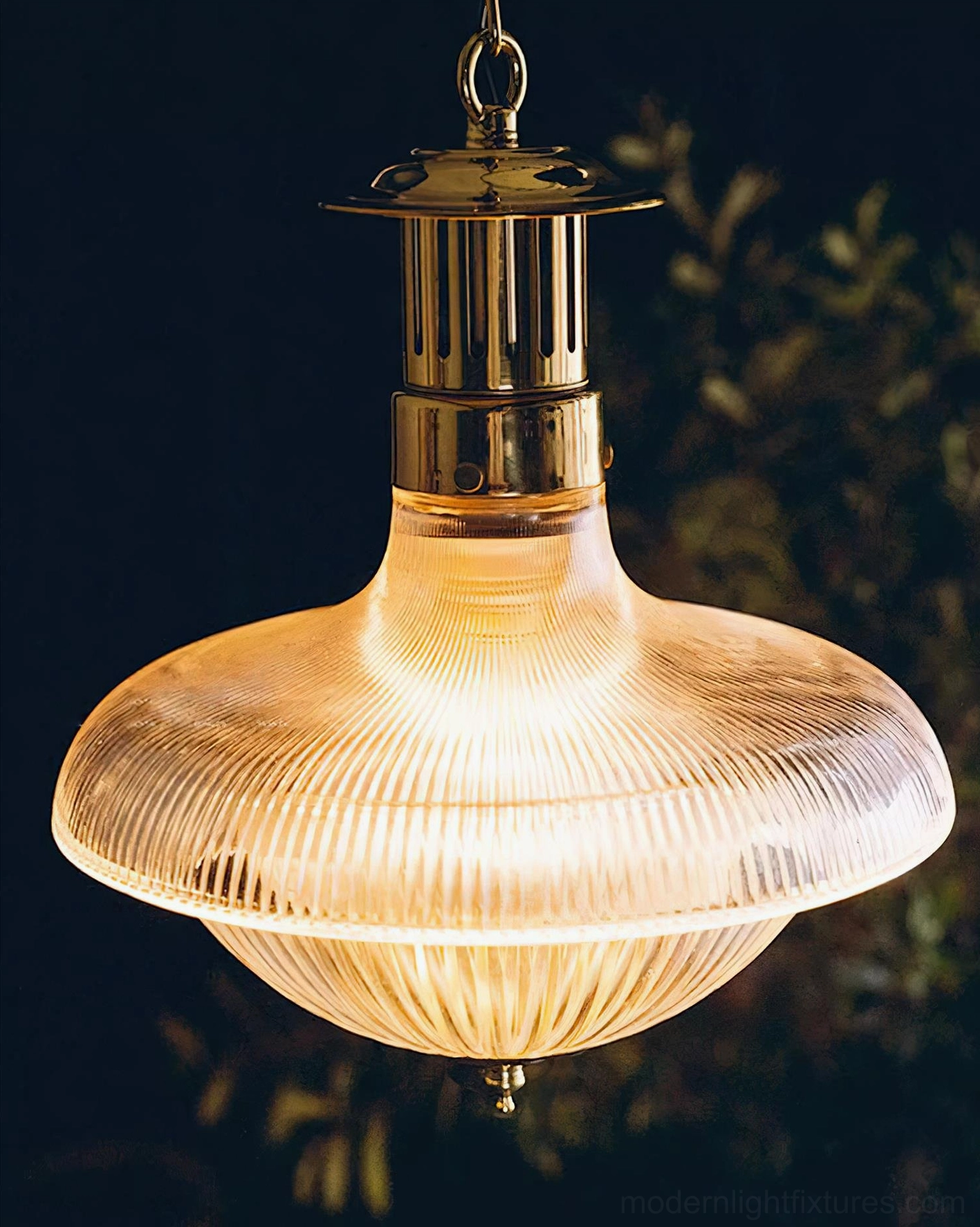 Lit vintage rippled glass pendant light with warm light diffusion, curved wide ribbed shade with green foliage backdrop