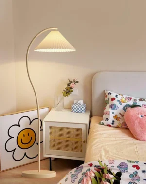 Beige Tove pleated floor lamp positioned beside bedroom nightstand with warm ambient lighting
