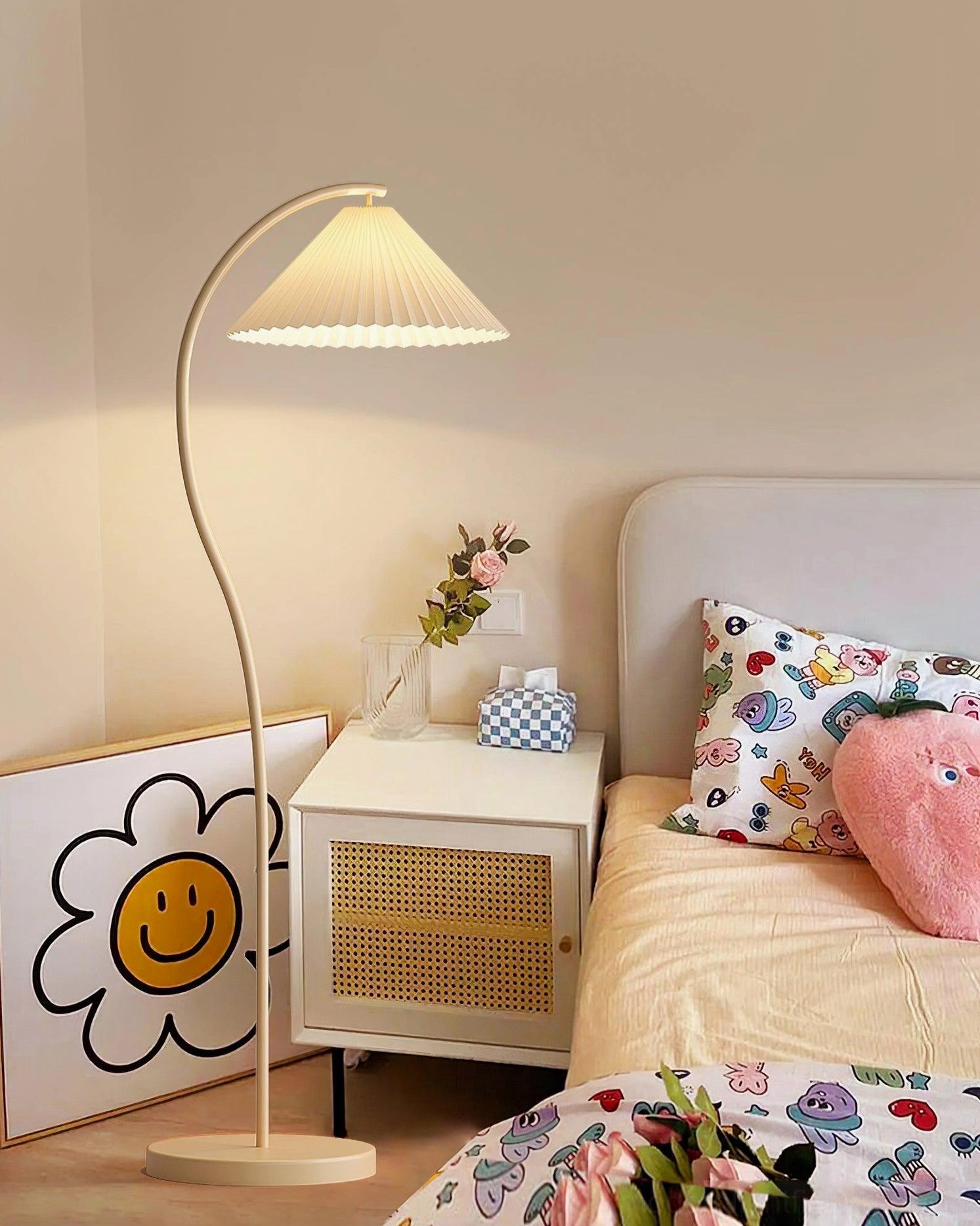 Beige Tove pleated floor lamp positioned beside bedroom nightstand with warm ambient lighting