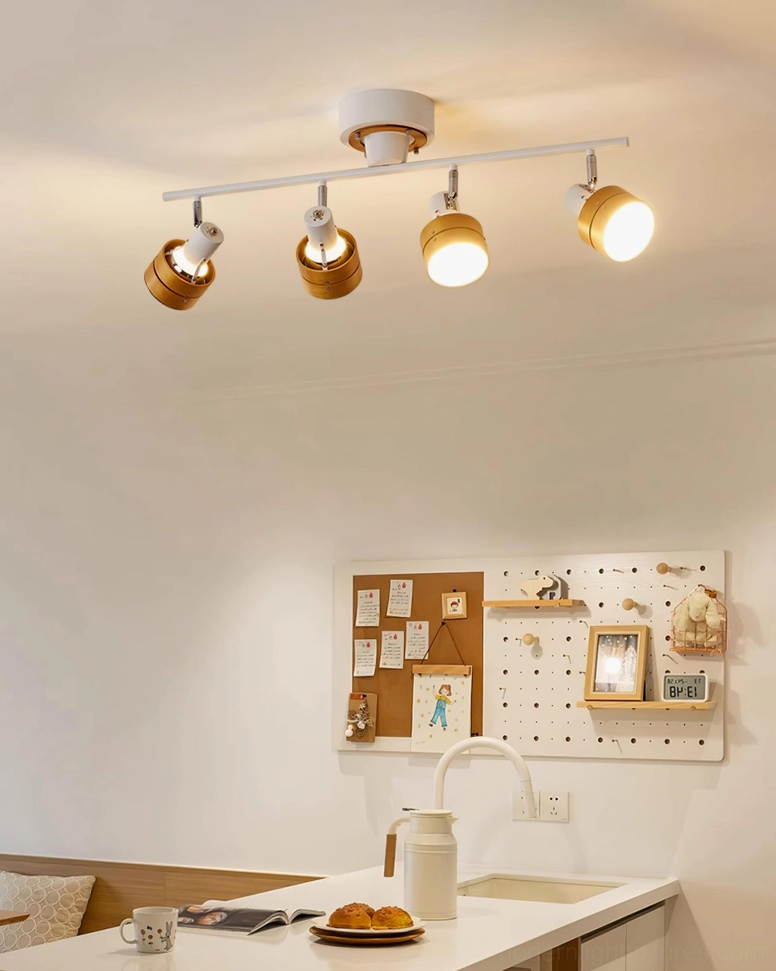 Four-head track lighting with white metal base and light wood tone lamp shades over kitchen breakfast bar