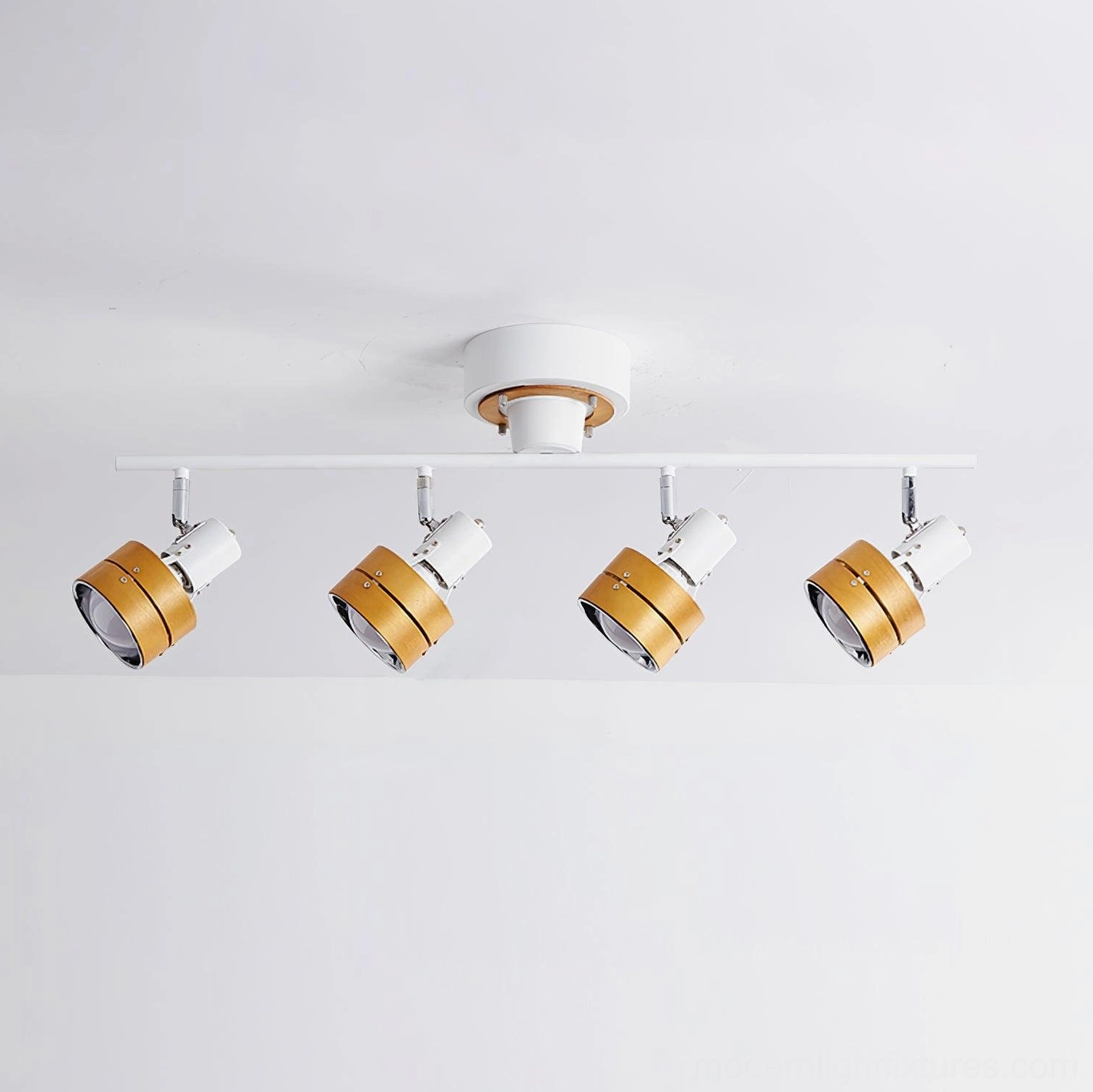 Four-head track spotlight fixture with white metal frame and light wood tone finishes on white background