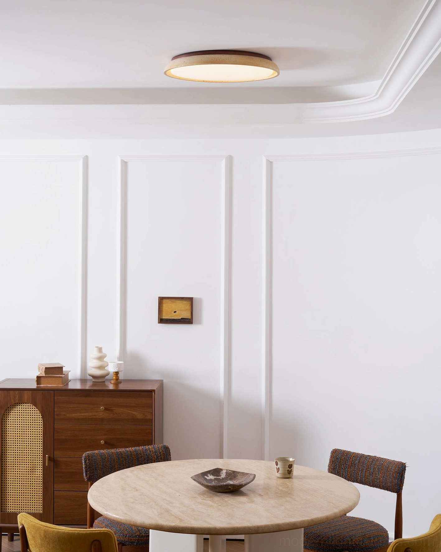 Travertine flush mount ceiling light casting warm glow over dining area with neutral decor