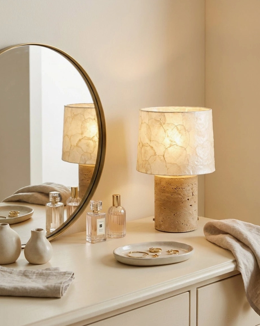 Travertine base table lamp on bedroom vanity with round mirror styling