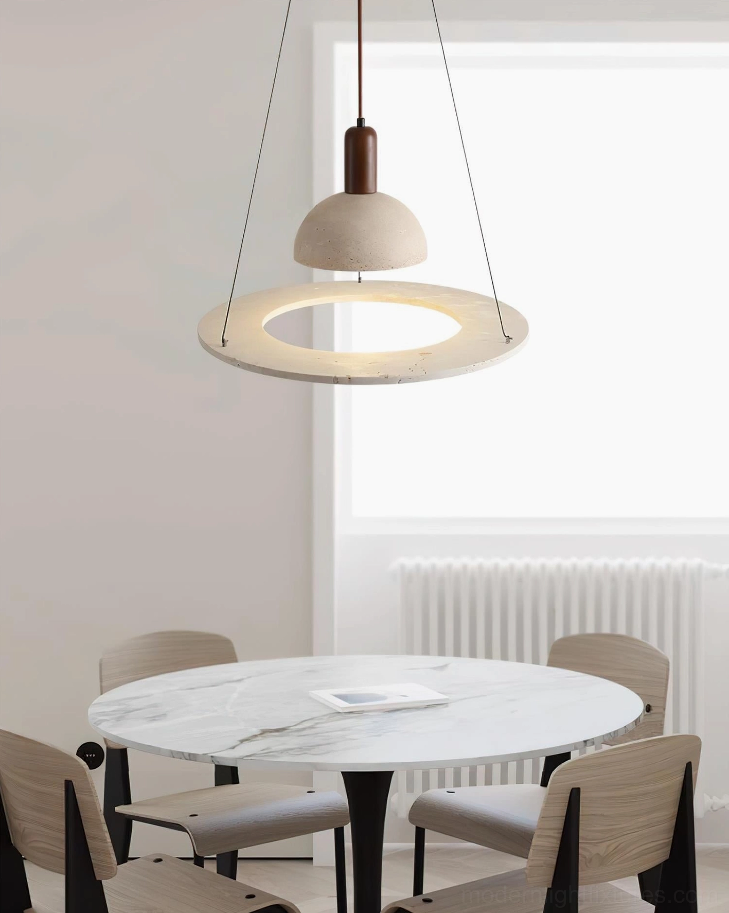 Side angle of travertine pendant light with backlit hollow ring above marble dining table