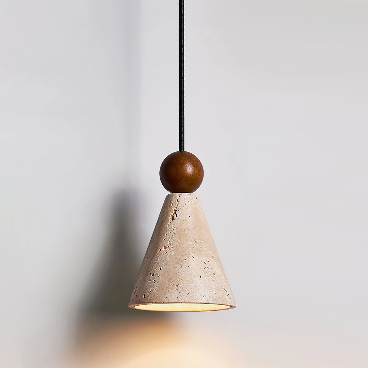 Travertine cone pendant with black fabric hanging cord and warm light activated