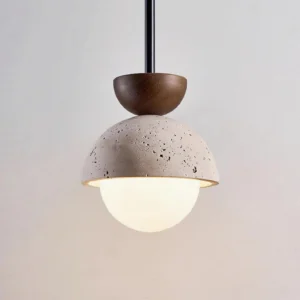 Minimalist pendant light with porous travertine shade and warm light cast on off-white wall showing concrete texture detail