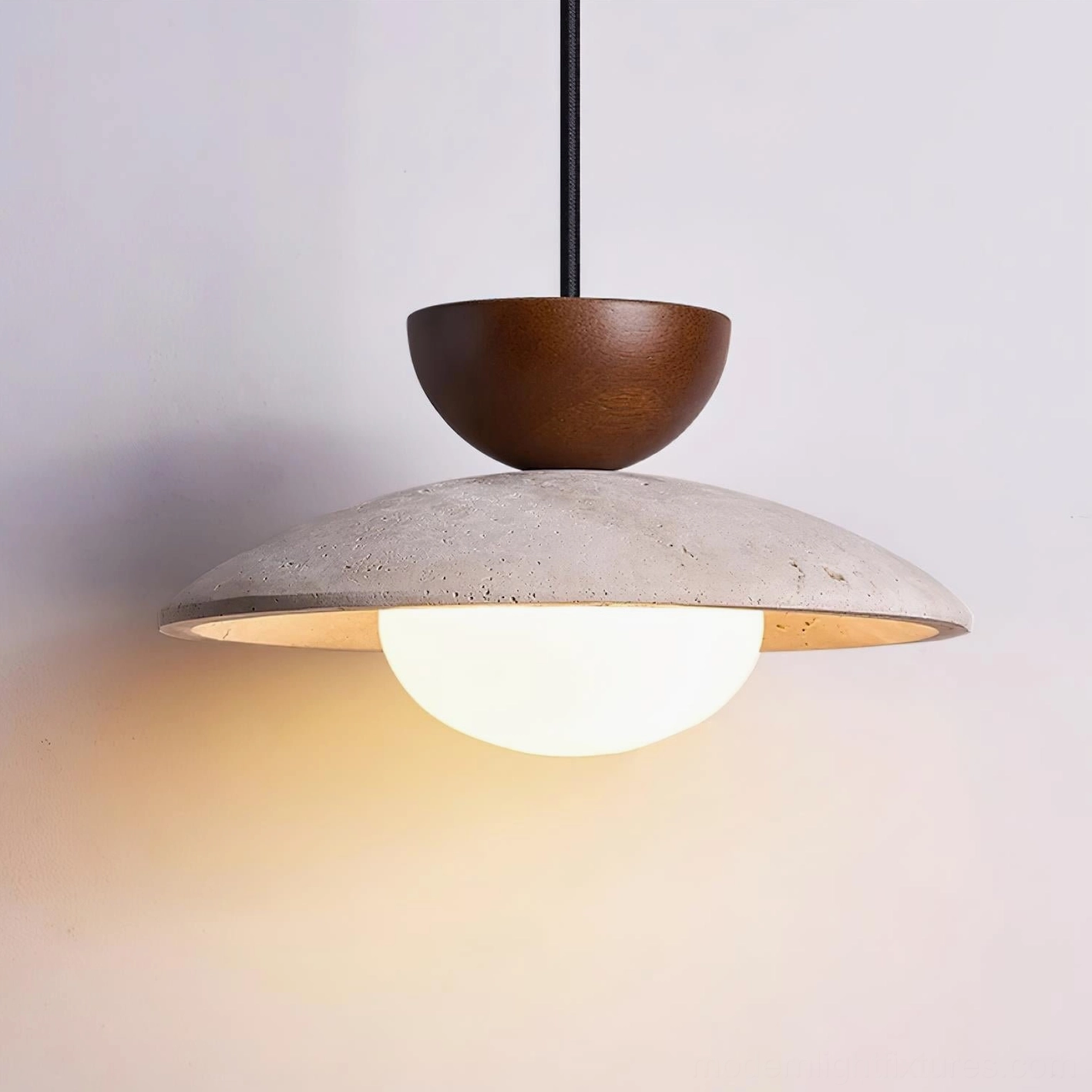 Illuminated Tia travertine pendant light showing frosted glass sphere glow through stone disc, side view