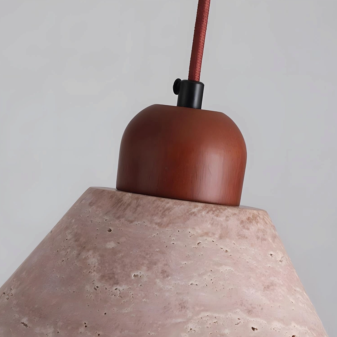 Modern travertine pendant light installation detail showing cone shade, wood fixture cap, electrical components, and suspension system