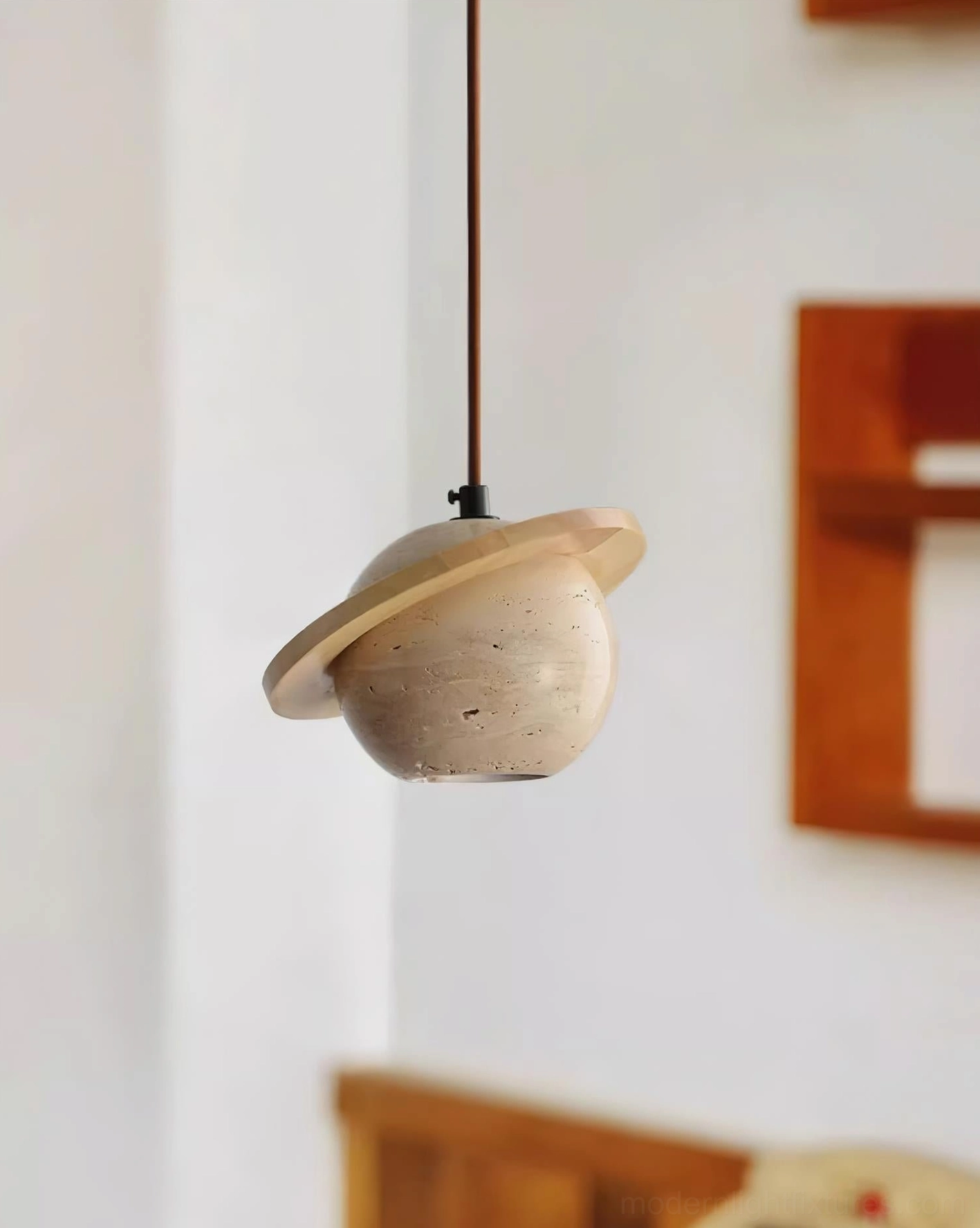 Low-angle side view of travertine pendant fixture with warm wood decor backdrop, contemporary minimalist aesthetic