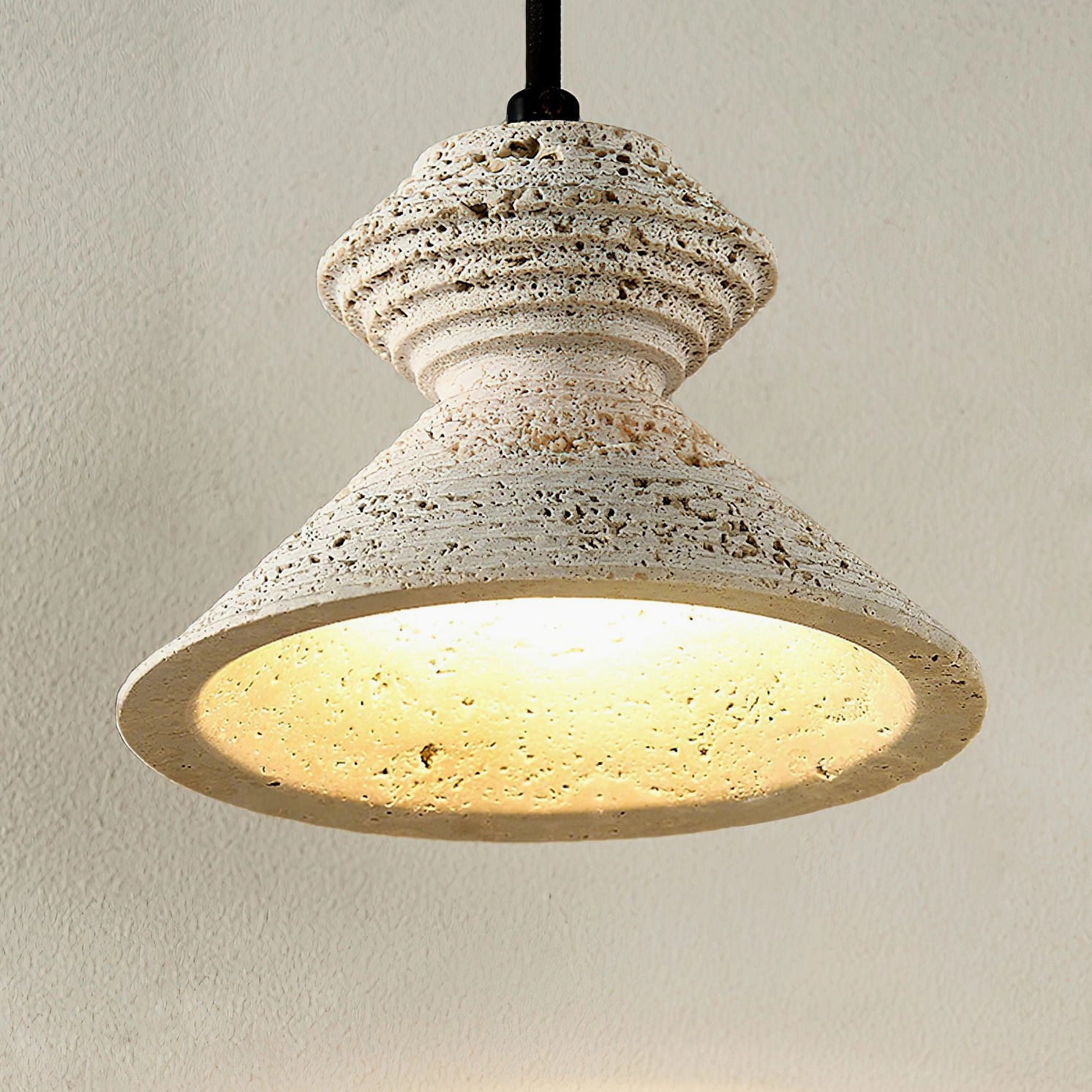 Multiple travertine pendant lights hanging at varied heights creating layered wabi-sabi aesthetic display