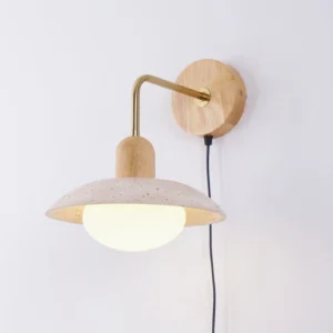 Modern travertine stone wall lamp with black power cord and integrated switch, angled perspective showing brass fixtures and stone texture