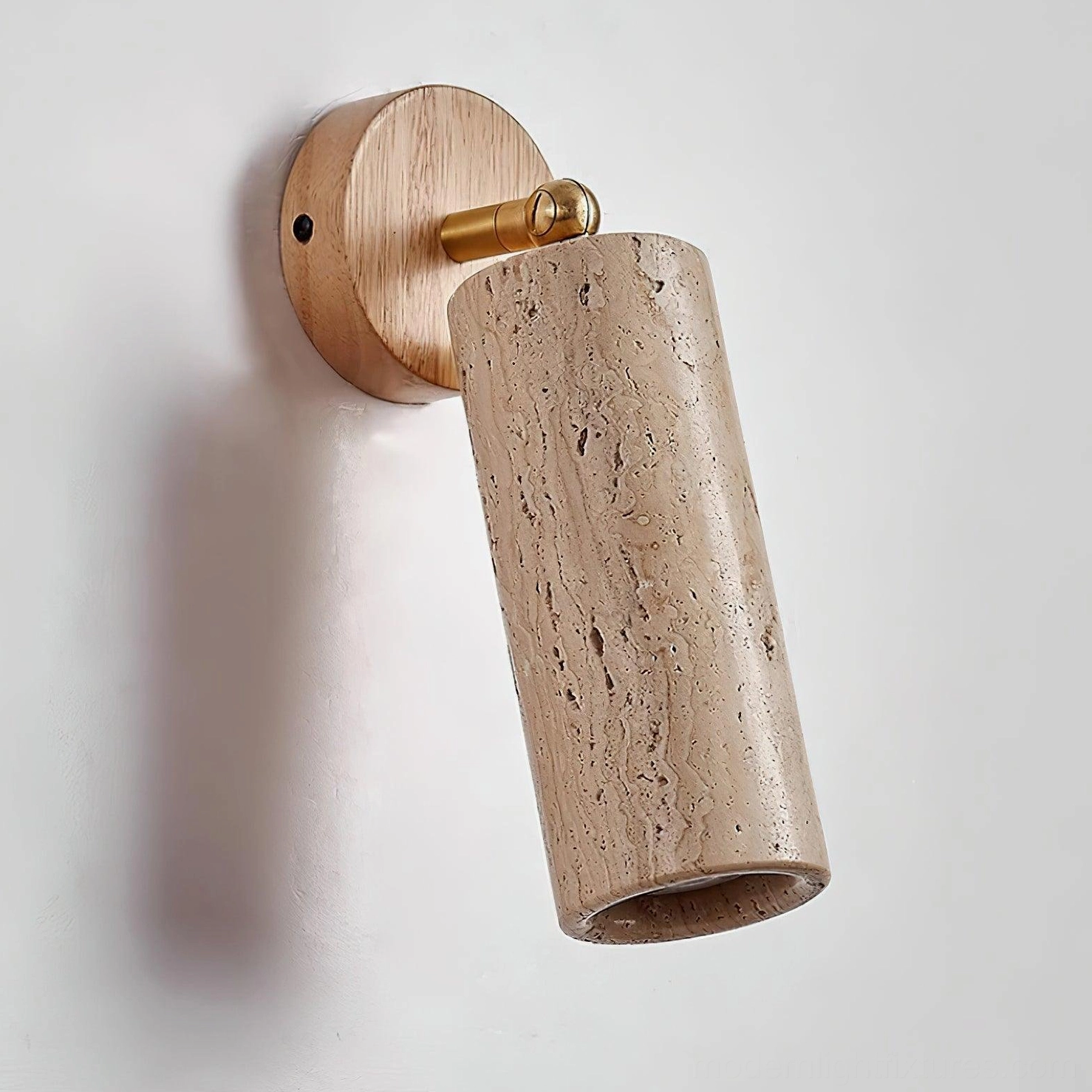 Mireille travertine wall sconce with brass swivel mechanism allowing flexible directional light adjustment